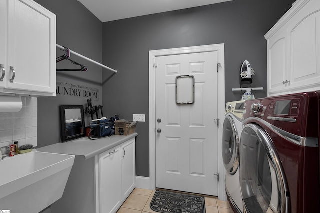 laundry area with light tile patterned floors, washer and clothes dryer, a sink, and cabinet space