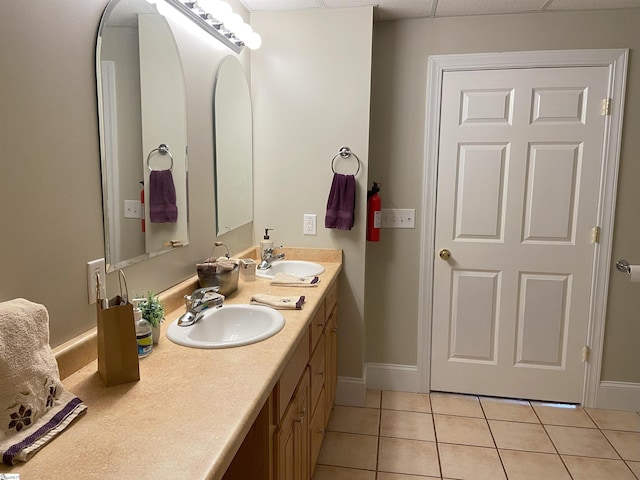 bathroom featuring baseboards, double vanity, a sink, and tile patterned floors