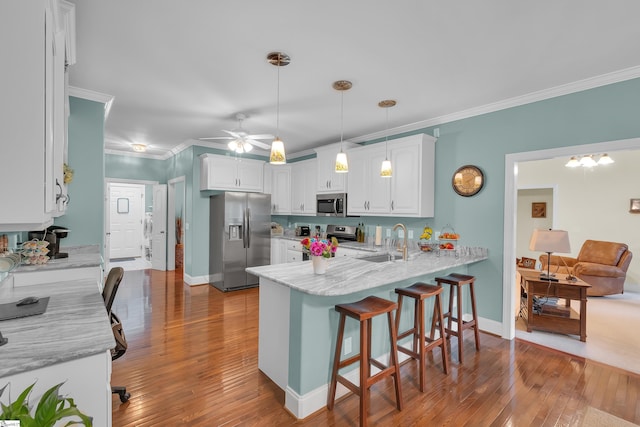 kitchen featuring stainless steel appliances, white cabinetry, a sink, and a peninsula