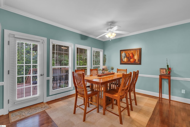 dining area featuring light wood-type flooring, baseboards, a ceiling fan, and crown molding