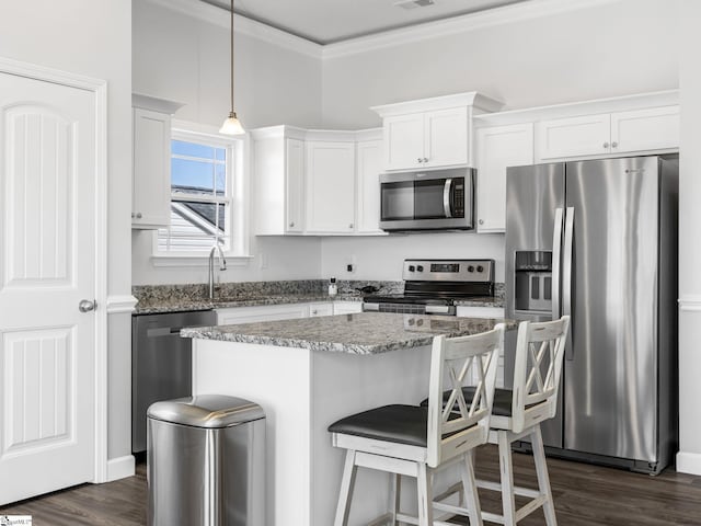kitchen featuring white cabinetry, appliances with stainless steel finishes, crown molding, and a center island