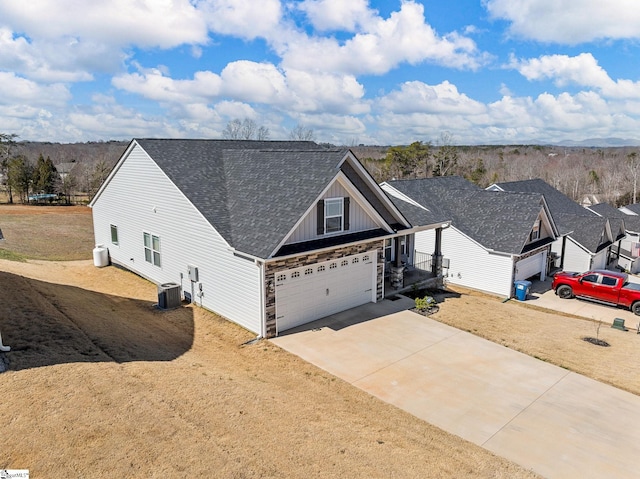 view of front facade with an attached garage, cooling unit, a shingled roof, concrete driveway, and board and batten siding