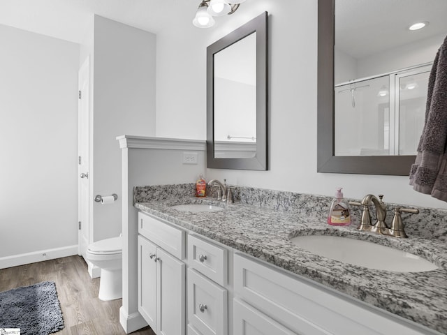 full bathroom with double vanity, wood finished floors, a sink, and toilet