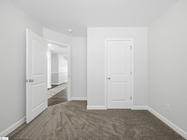 unfurnished bedroom with a textured ceiling, baseboards, and carpet flooring