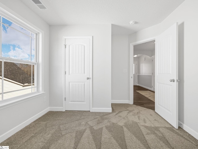unfurnished bedroom with carpet floors, visible vents, and baseboards