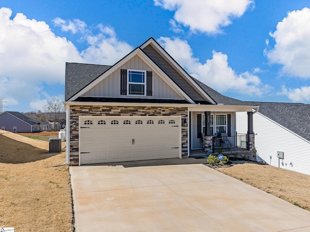 craftsman-style house with a garage, concrete driveway, stone siding, covered porch, and board and batten siding