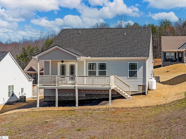 rear view of house featuring a deck, a yard, roof with shingles, and central air condition unit