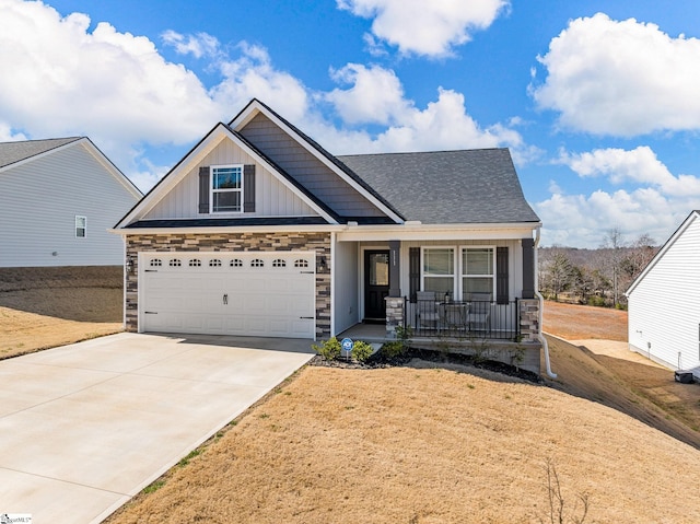 craftsman-style home with a garage, concrete driveway, stone siding, a porch, and board and batten siding