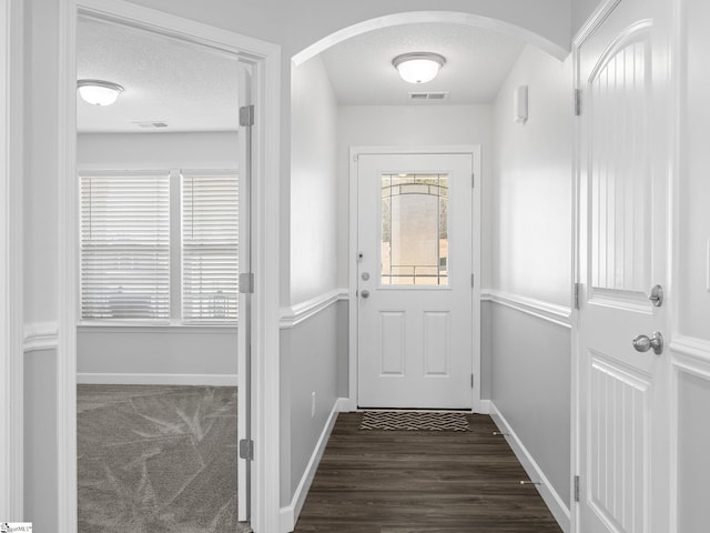 entryway featuring baseboards, visible vents, arched walkways, and a textured ceiling