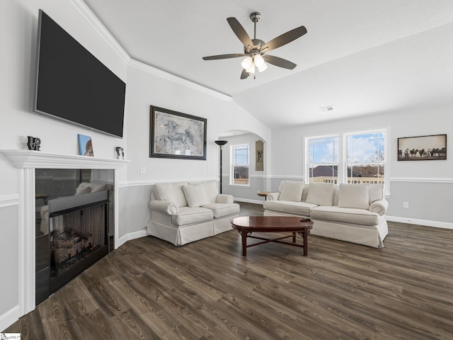 living room featuring arched walkways, a fireplace, dark wood-type flooring, a ceiling fan, and baseboards
