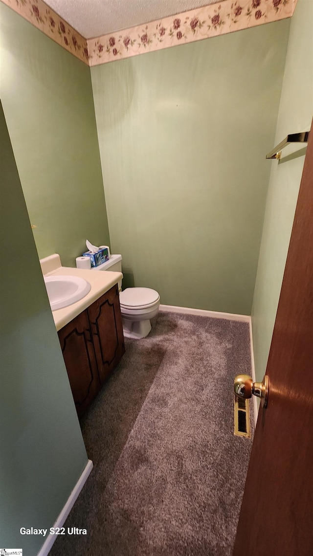 bathroom with toilet, a textured ceiling, vanity, and baseboards