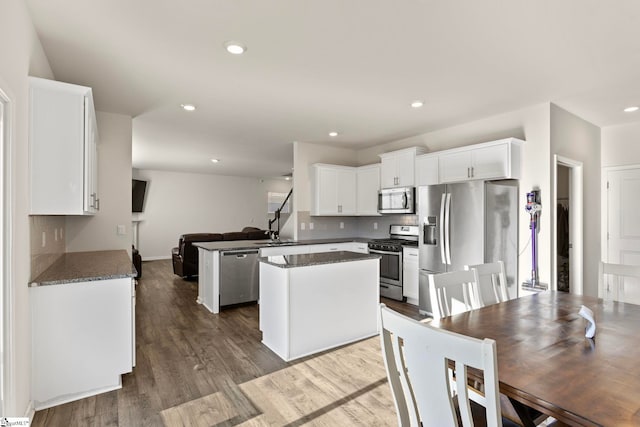 kitchen featuring dark wood-style flooring, appliances with stainless steel finishes, open floor plan, white cabinets, and a kitchen island