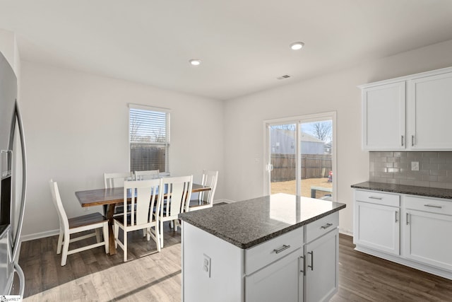 kitchen with dark stone countertops, dark wood finished floors, backsplash, and stainless steel fridge with ice dispenser