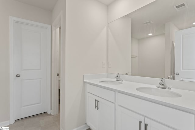 full bath featuring double vanity, a sink, visible vents, and baseboards