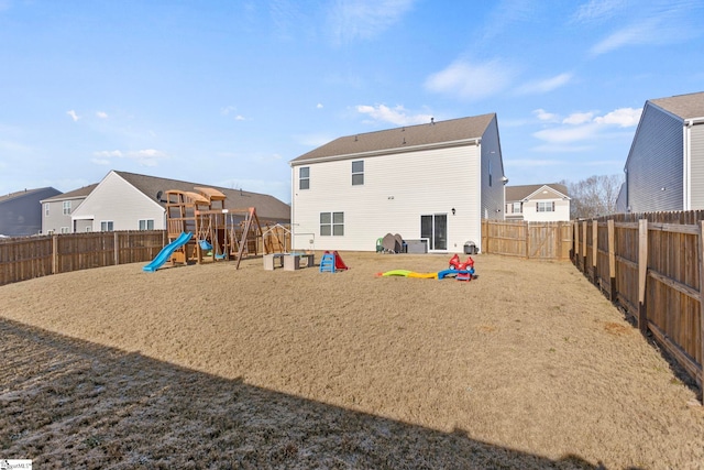 rear view of house with a fenced backyard and a playground