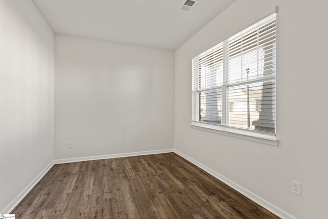 unfurnished room with baseboards, visible vents, and dark wood-style flooring