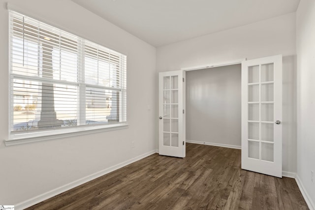 empty room with baseboards, wood finished floors, and french doors