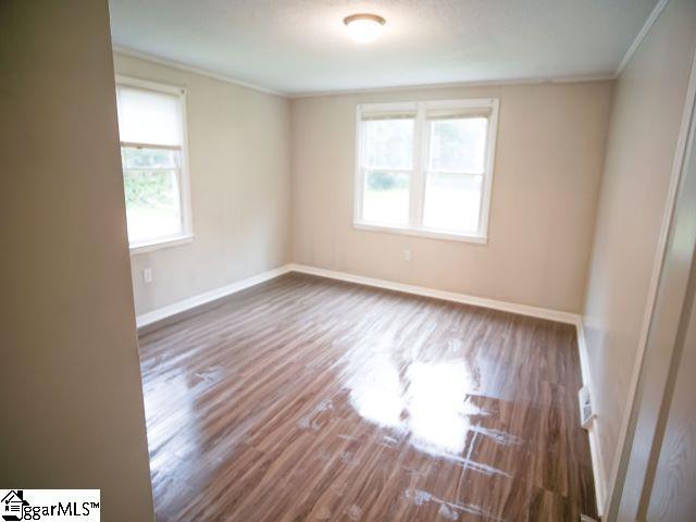 unfurnished room featuring a healthy amount of sunlight, baseboards, and wood finished floors