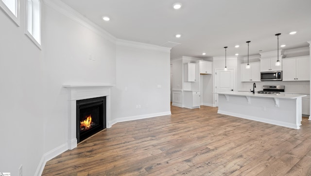 1791 Wabash Pl Lot 0511, Boiling Springs, SC 29316 - unfurnished living room with recessed lighting, light wood finished floors, baseboards, ornamental molding, and a warm lit fireplace