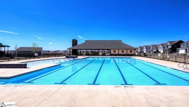 community pool featuring a residential view, a patio area, and fence