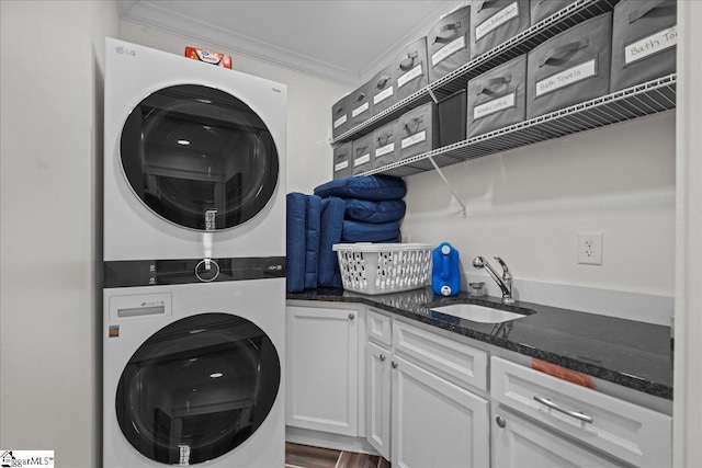 clothes washing area with a sink, cabinet space, ornamental molding, and stacked washer / dryer