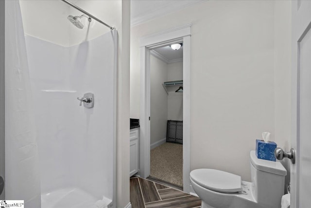 bathroom featuring a stall shower, wood finished floors, toilet, and crown molding