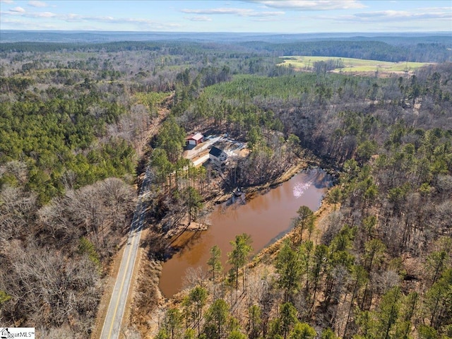 birds eye view of property with a water view and a wooded view