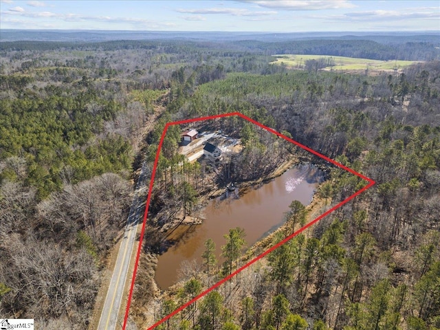 drone / aerial view featuring a water view and a forest view