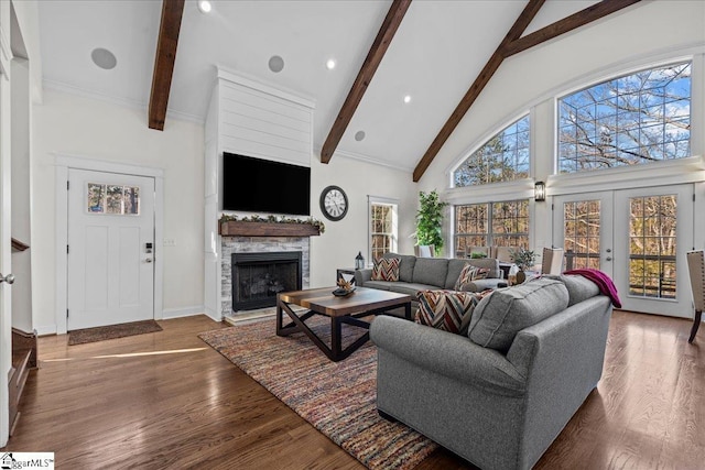 living area with high vaulted ceiling, beamed ceiling, a stone fireplace, and wood finished floors