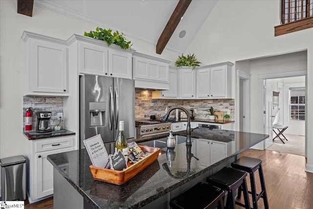 kitchen with dark wood-style flooring, appliances with stainless steel finishes, a sink, beamed ceiling, and a kitchen bar