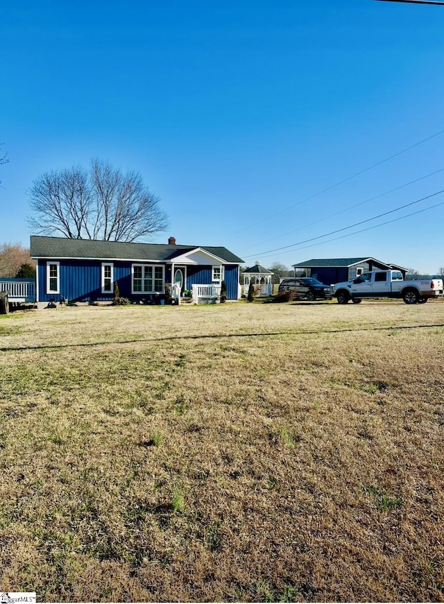 ranch-style home with board and batten siding, a front yard, and covered porch