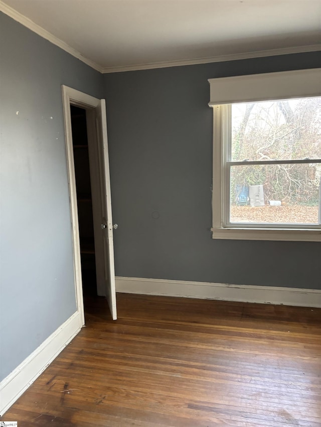 unfurnished room featuring crown molding, baseboards, and wood finished floors