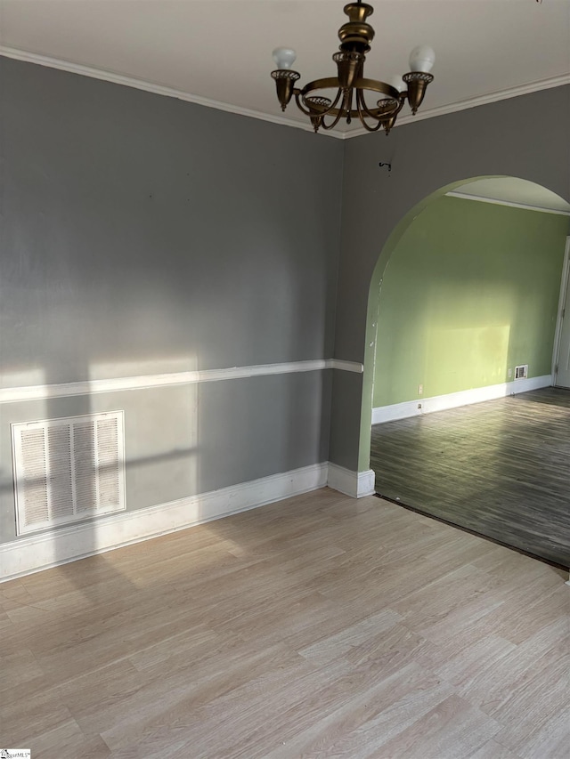 unfurnished room with ornamental molding, visible vents, arched walkways, and a chandelier