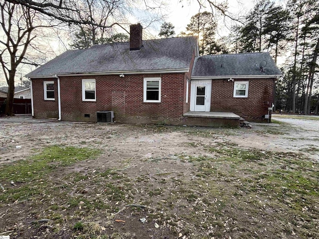 rear view of house with a chimney, roof with shingles, crawl space, central AC, and brick siding