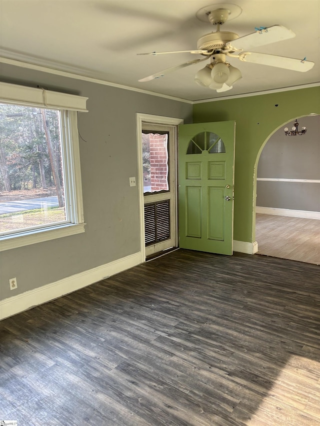 unfurnished room featuring dark wood-style floors, arched walkways, crown molding, and baseboards