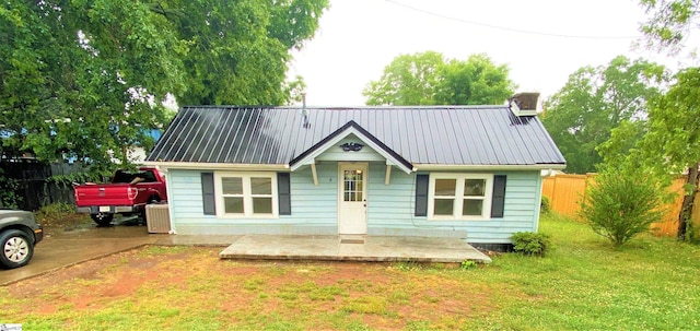 bungalow featuring a front yard, metal roof, and fence