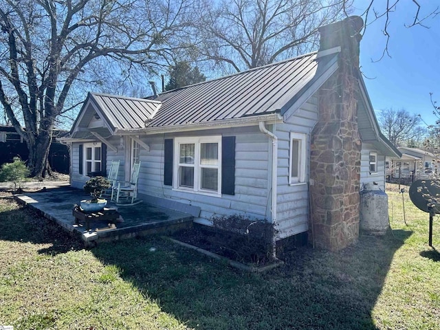 view of side of home with metal roof, a standing seam roof, and a chimney