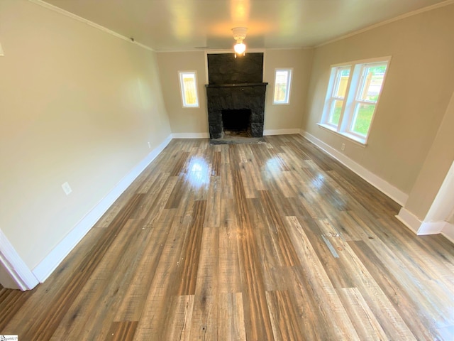 unfurnished living room featuring ornamental molding, a fireplace, wood finished floors, and baseboards