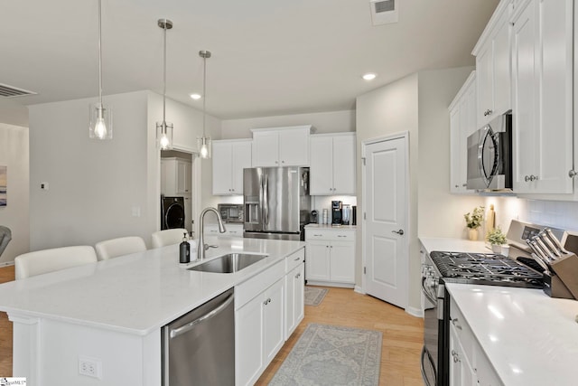 kitchen with visible vents, a center island with sink, appliances with stainless steel finishes, and a sink