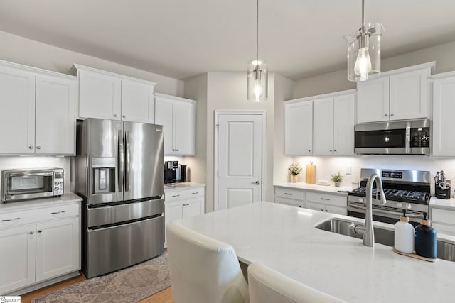 kitchen featuring white cabinetry, tasteful backsplash, appliances with stainless steel finishes, and decorative light fixtures