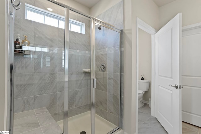 bathroom with marble finish floor, a shower stall, and toilet