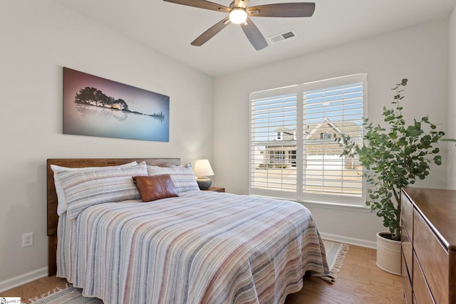 bedroom featuring a ceiling fan, light wood-type flooring, visible vents, and baseboards