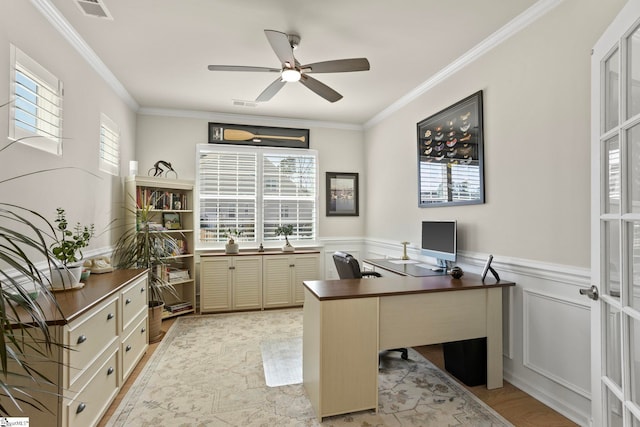 office with ornamental molding, a wainscoted wall, visible vents, and a ceiling fan