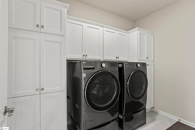 clothes washing area with independent washer and dryer, cabinet space, and baseboards