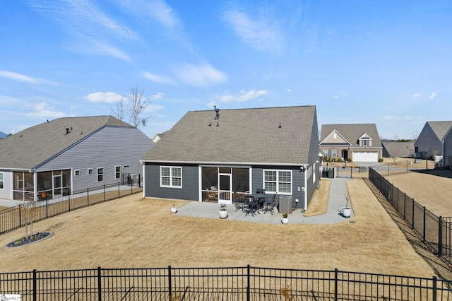 rear view of house featuring a shingled roof, a sunroom, a patio area, and a fenced backyard