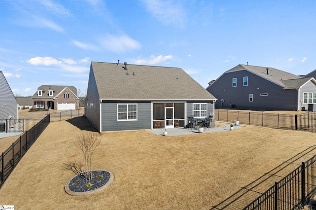 back of house featuring roof with shingles, a lawn, a patio area, and a fenced backyard