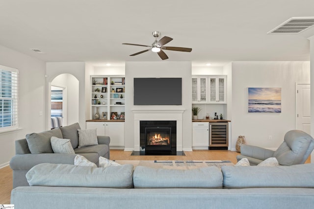 living area with a fireplace with flush hearth, wine cooler, visible vents, and light wood-style flooring