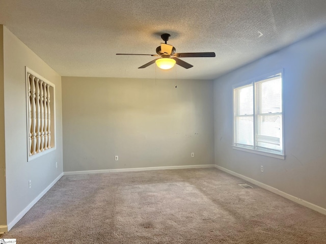 spare room featuring a textured ceiling, visible vents, a ceiling fan, baseboards, and carpet