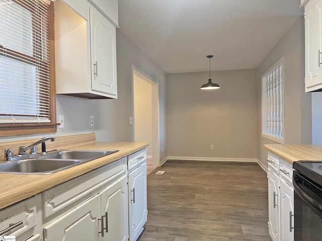 kitchen featuring baseboards, dark wood-style flooring, light countertops, white cabinetry, and a sink