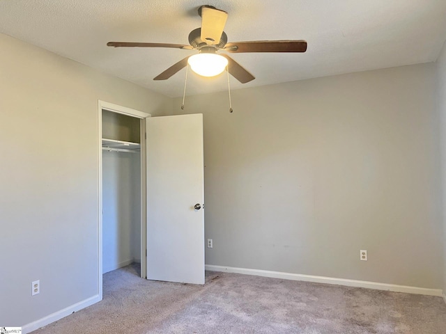 unfurnished bedroom with a closet, light carpet, ceiling fan, and baseboards